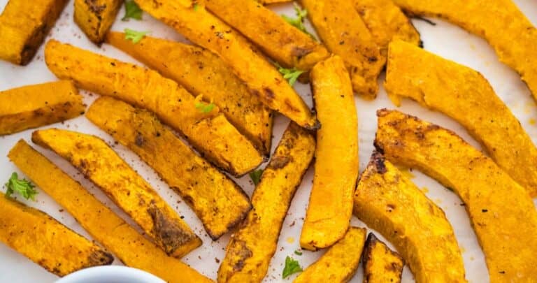 A plate of sweet potato pumpkin fries with ketchup and dipping sauce.