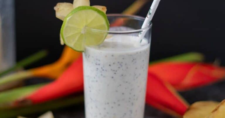 star fruit smoothie in a tall glass with a straw and sliced lime on the rim