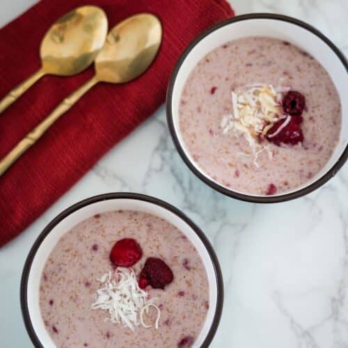 Two bowls of oatmeal with raspberries and coconut.
